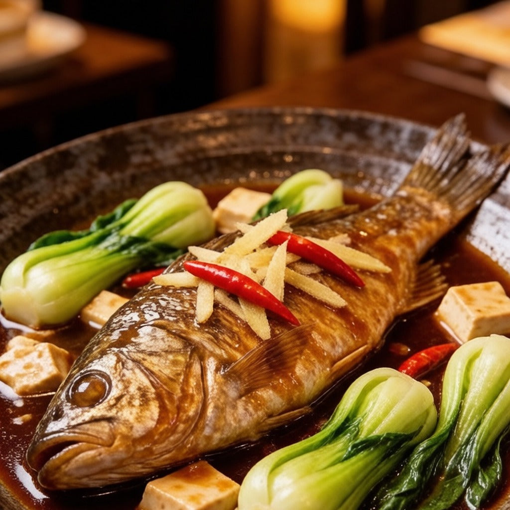 Whole sea bass braised in a dark pan with bok choy and chilli